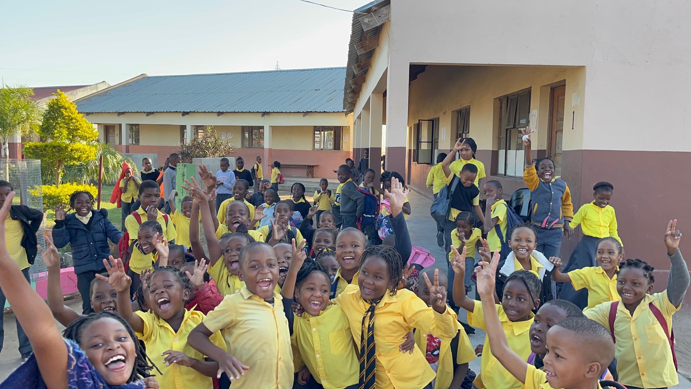 Children waving and smiling at school in Chokwe